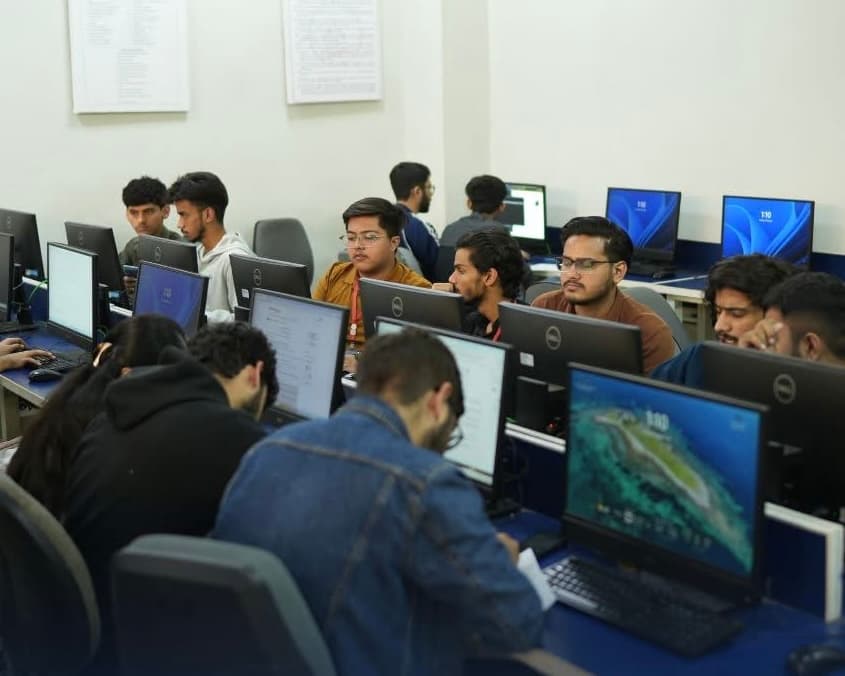 Male students coding on laptops in a classroom
